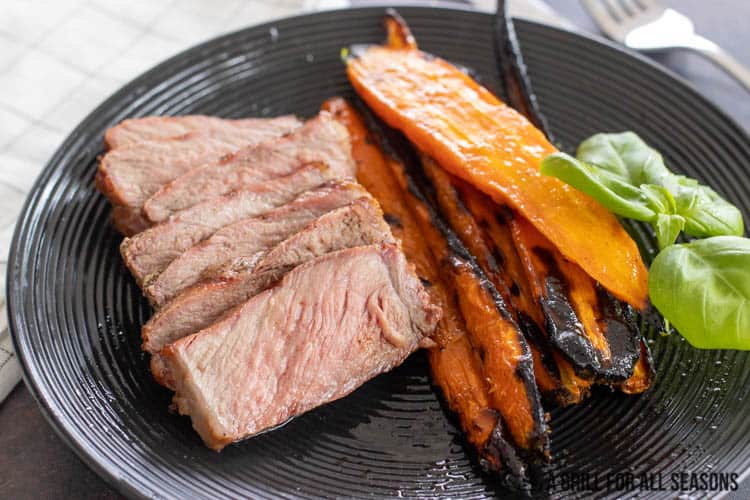 sliced beef on a plate next to carrots