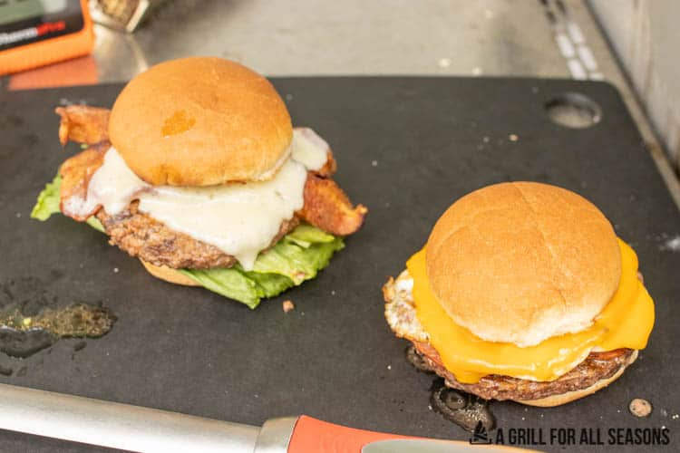 two burgers on cutting board