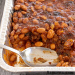 close up of spoon in pan of traeger smoked baked beans