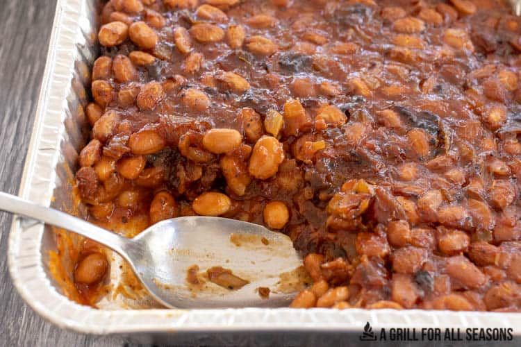 spoon in tray of smoked baked beans