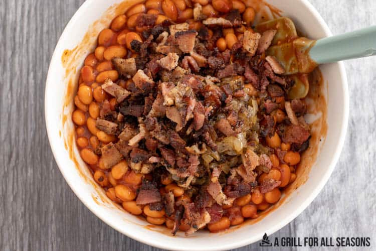 beans in bowl with sauce topped with bacon and onions