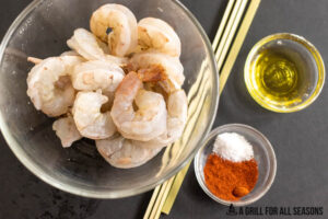 raw prawns in bowl next to small dish of oil and dry rub