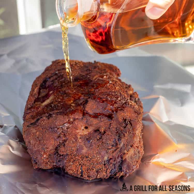 bourbon whiskey being poured over the beef roast