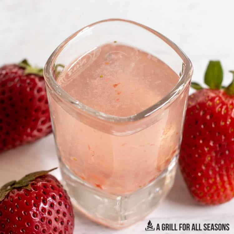 small glass with strawberry vodka shot surrounded by fresh berries