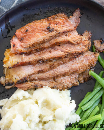 close up of sliced traeger ribeye steak on a plate with mashed potatoes