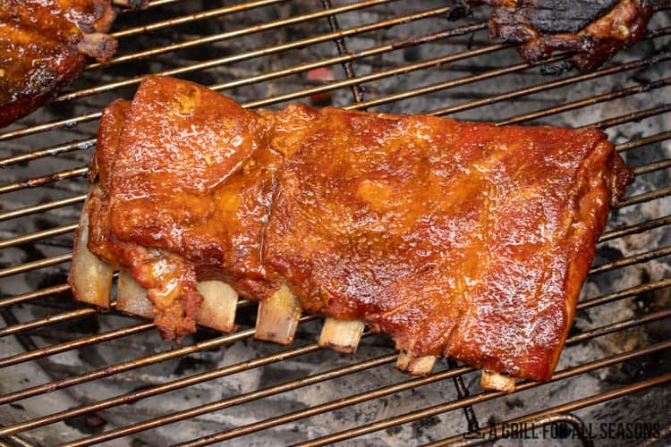 rack of ribs on grill being cooked with 3 2 1 ribs method