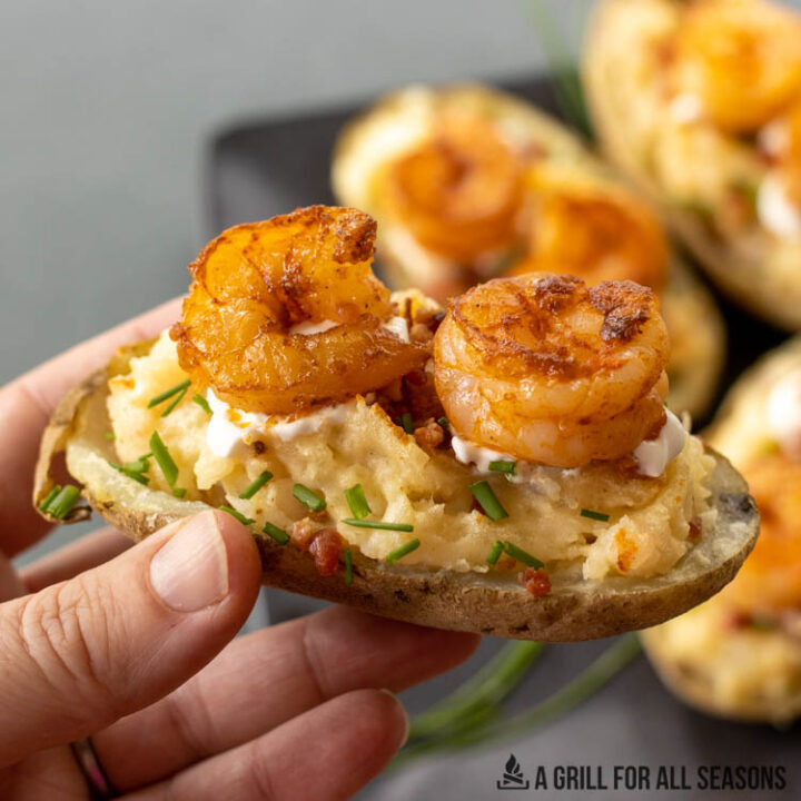 hand holding up a twice baked potato with shrimp
