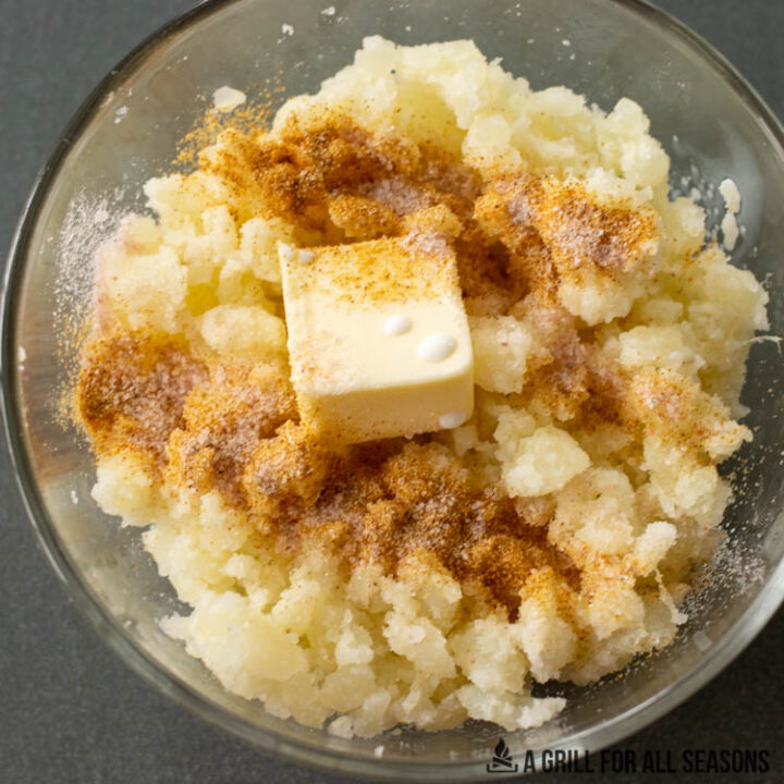 bowl of mashed potatoes with butter and seasoning on top