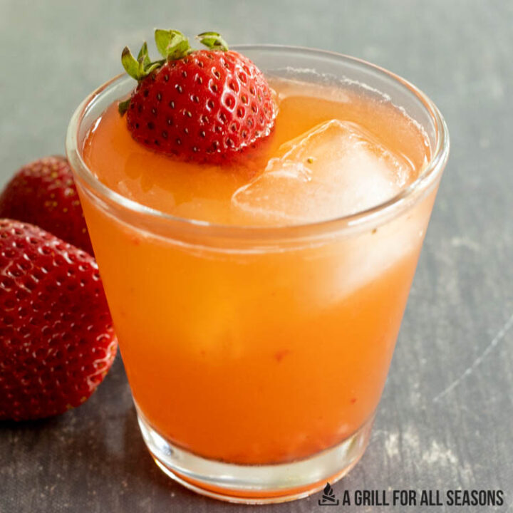 side view of glass of strawberry sour garnished with small strawberry