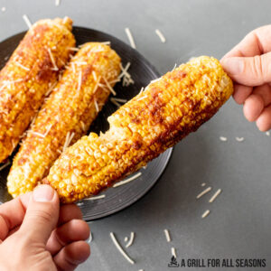hands holding a piece of traeger corn on the cob with a bite missing