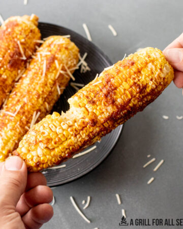 hands holding a piece of traeger corn on the cob with a bite missing