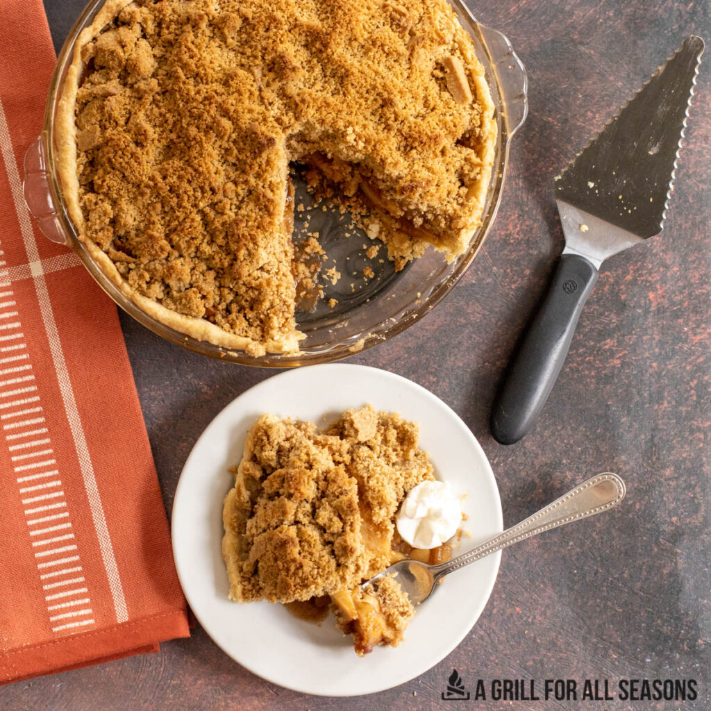 smoked apple pie with crumb topping from overhead with piece on plate