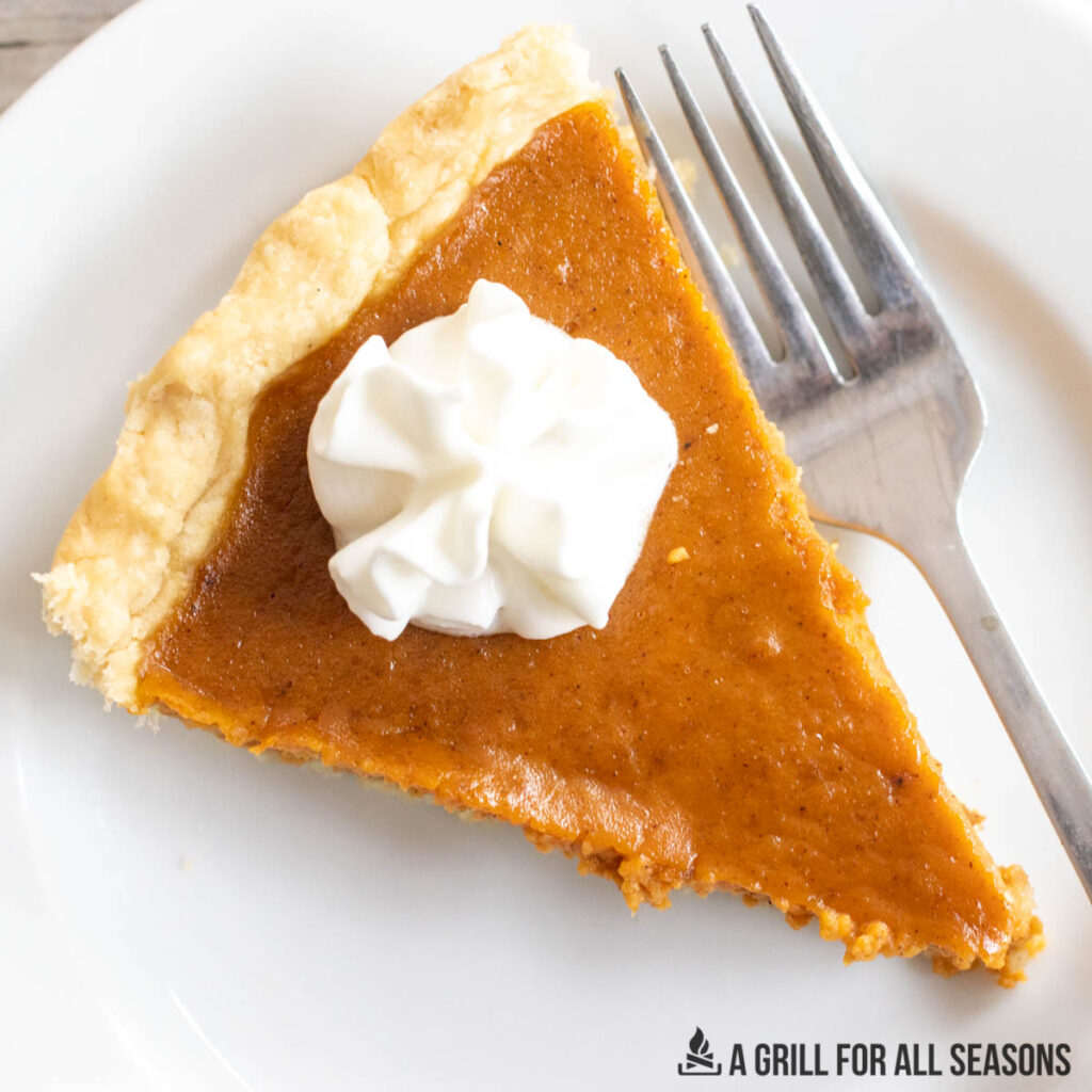 overhead shot of slice of smoked pumpkin pie on plate with whipped cream