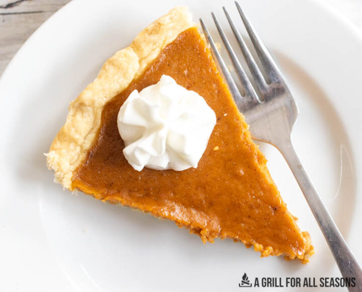 overhead shot of slice of smoked pumpkin pie on plate with whipped cream