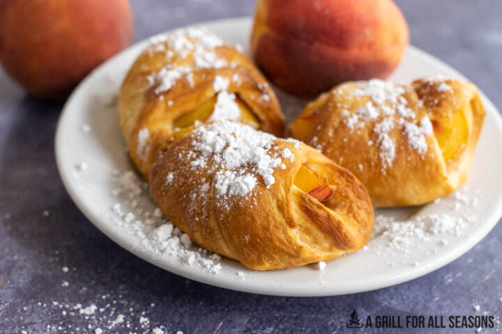 air fryer peaches on plate topped with powdered sugar