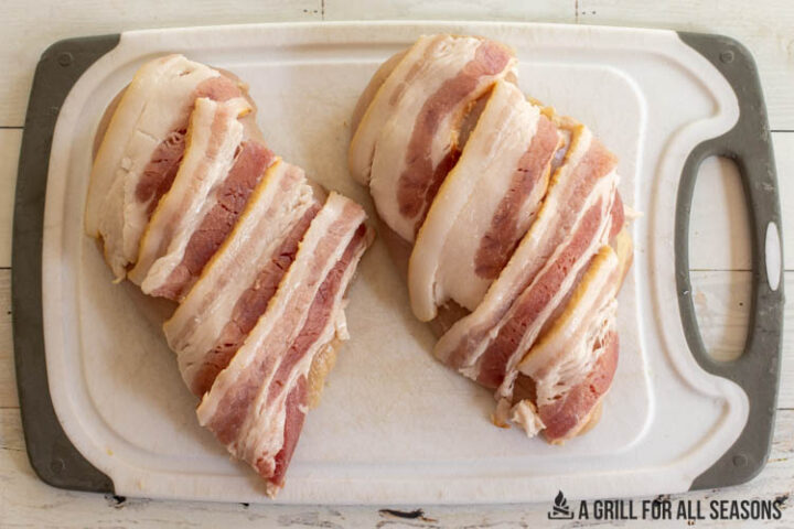 bacon on top of poultry on cutting board