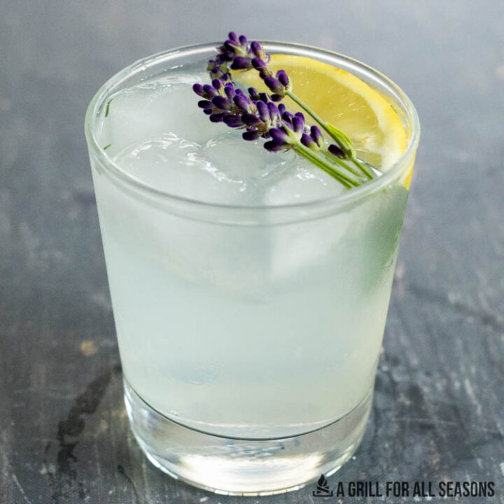 lavender lemonade cocktail garnished with flowers and lemon wedge