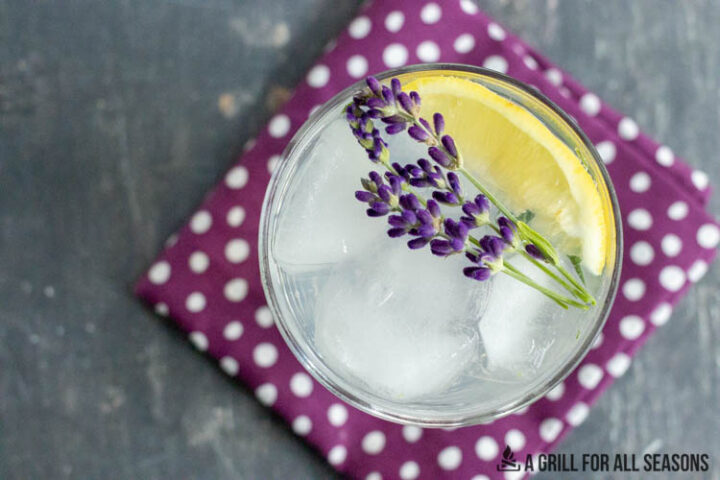 overhead shot of a lavender lemonade cocktail garnished with flowers and lemon wedge