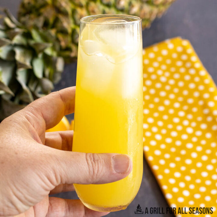 hand holding glass with pineapple screwdriver cocktail