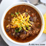 smoked chili recipe in a bowl topped with cheese
