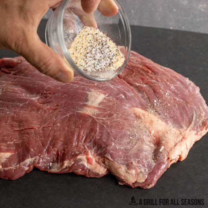 dry rub in small bowl being sprinkled on meat