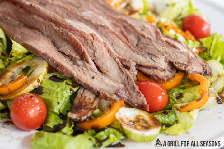 smoked flank steak slices served on top of a salad