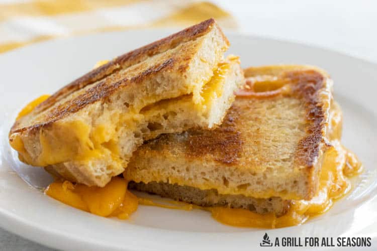 sourdough grilled cheese sandwich cut in half on a plate with a bite missing