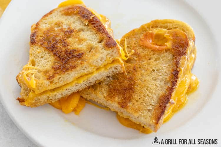 sourdough grilled cheese sandwich cut in half on a plate