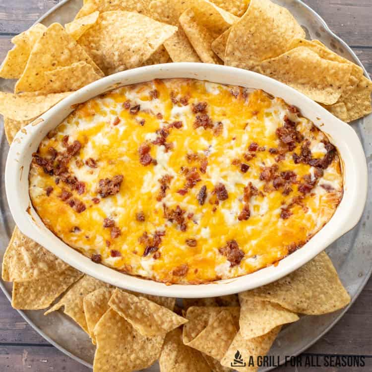 corn dip with cream cheese and bacon surrounded by tortilla chips