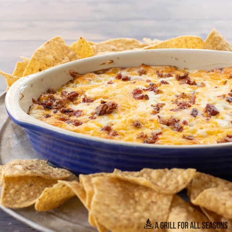 corn dip with cream cheese and bacon surrounded by tortilla chips