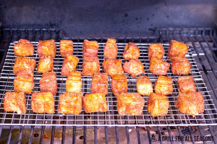 rack on traeger grill with cubes of pork belly