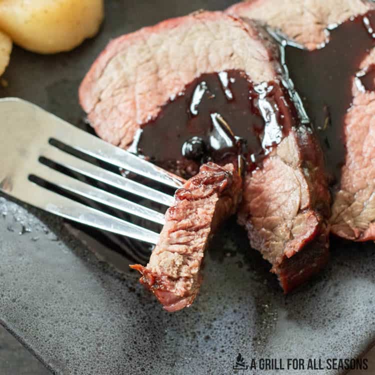 bite of smoked beef tenderloin on a fork close up