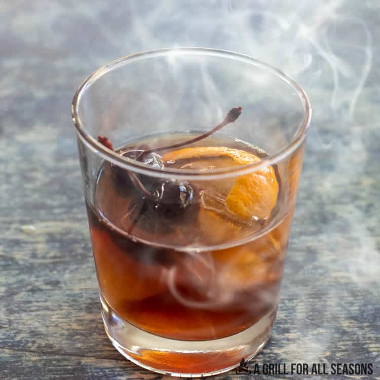smoke rising from glass of smoked old fashioned
