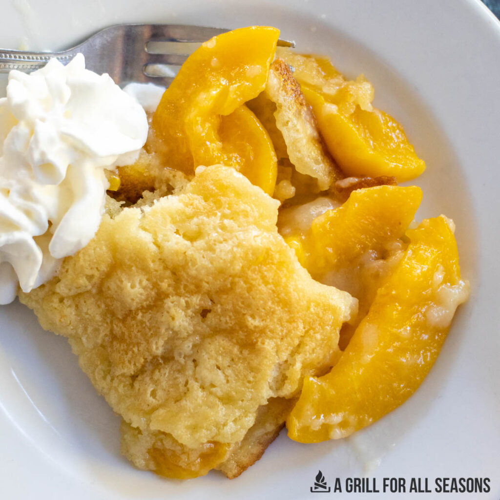 close up shot of a plate with smoked peach cobbler and whipped cream