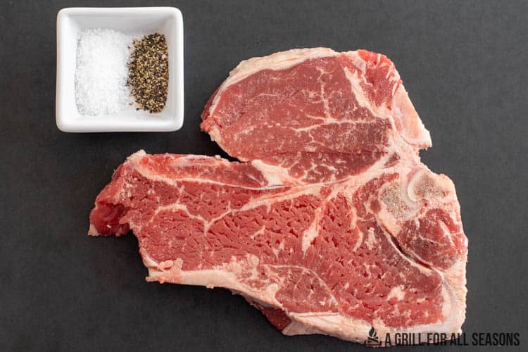t bone on cutting board with salt and pepper in small dish