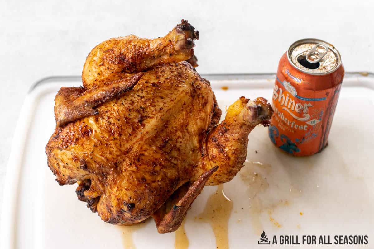 chicken resting on cutting board next to beer can
