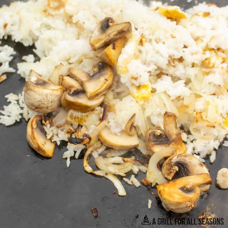 mushrooms, onions, garlic, and rice cooking on blackstone
