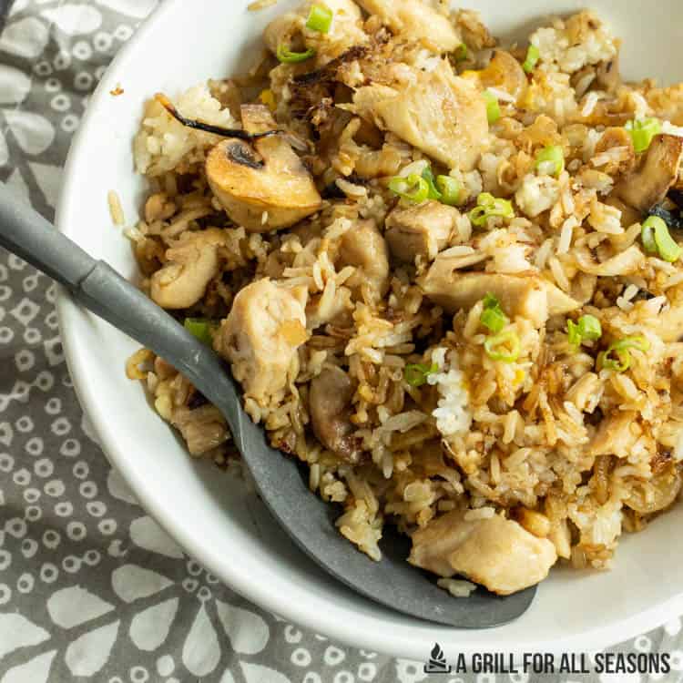 blackstone chicken fried rice in white bowl with large serving spoon