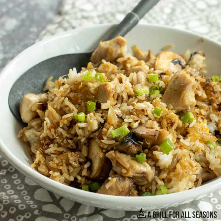blackstone chicken fried rice in white serving bowl with large metal spoon