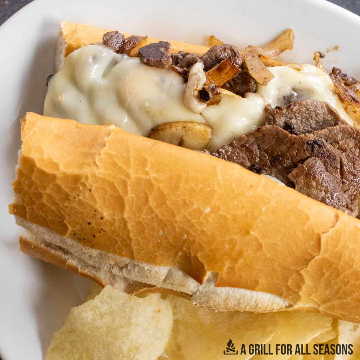 blackstone cooked philly cheesesteak in hero roll on white plate