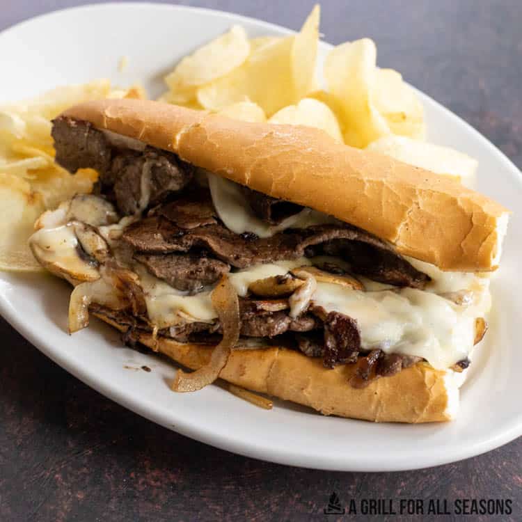 blackstone philly cheesesteak on white plate with potato chips