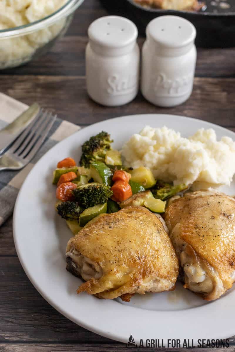 cast iron chicken on plate with vegetables and potatoes