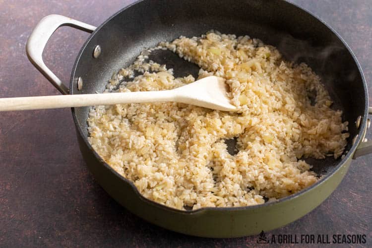 large skillet sauteing rice, onions