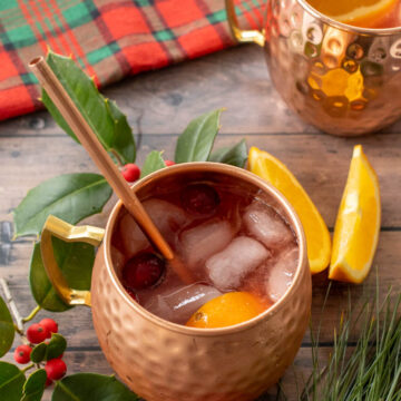 mugs with christmas moscow mule garnished with orange and cranberries