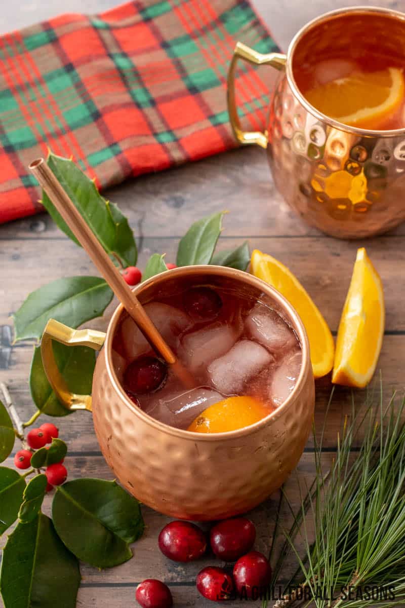 mugs with christmas moscow mule garnished with orange and cranberries