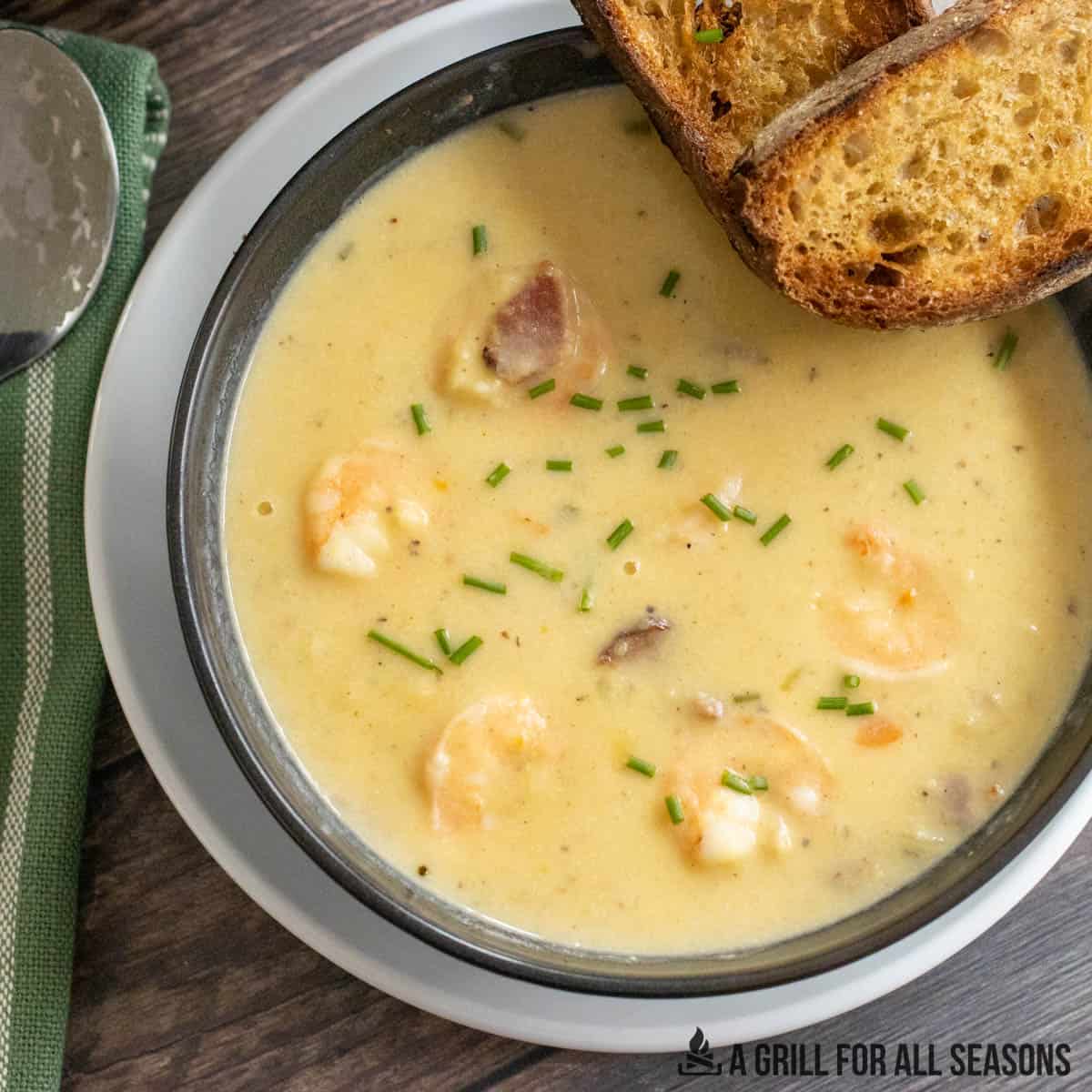 close up of shrimp and corn bisque in bowl with toasted bread