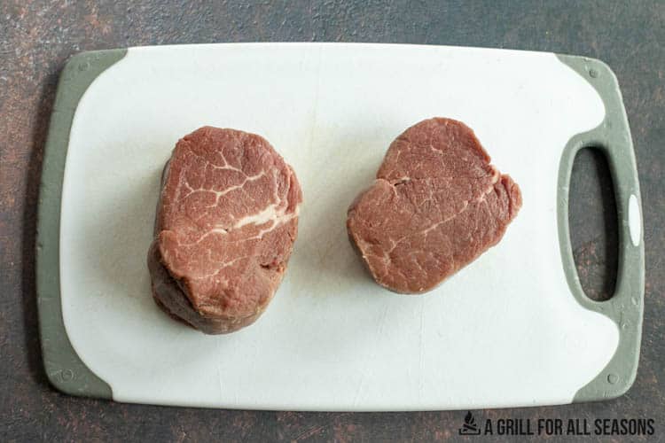 two beef tenderloin filets on white cutting board