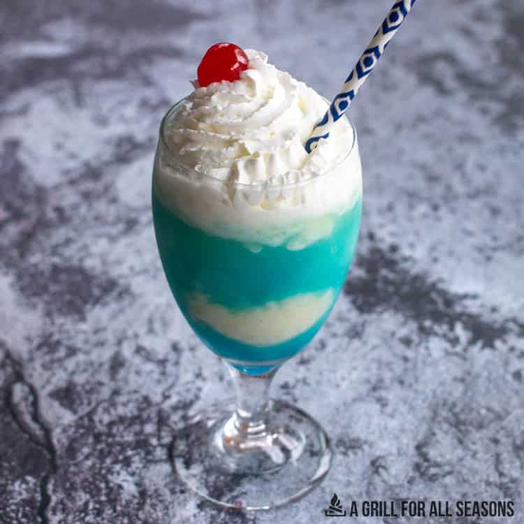 blue colada in glass with whipped cream, cherry, and straw