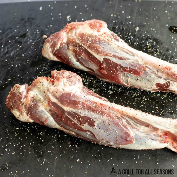 lamb shanks on a cutting board with salt and pepper