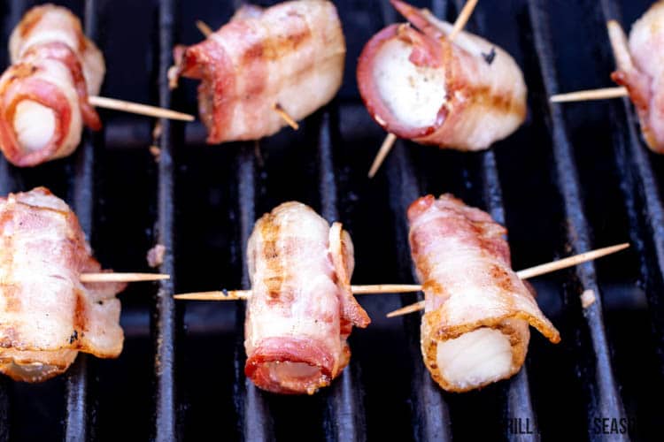 Bacon wrapped cod cooking on grill
